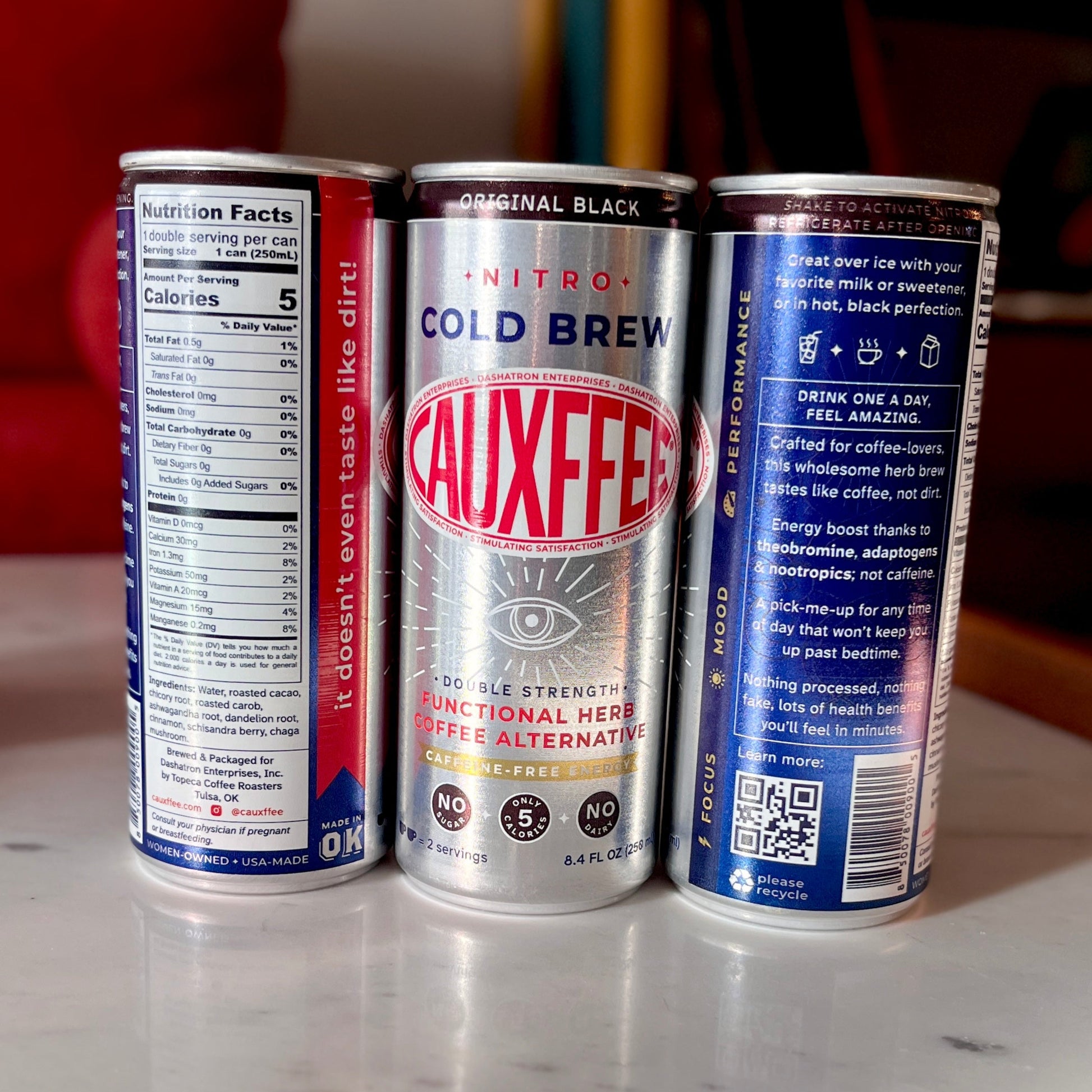 Three Cauxffee drink cans on a marble surface with a blurred background