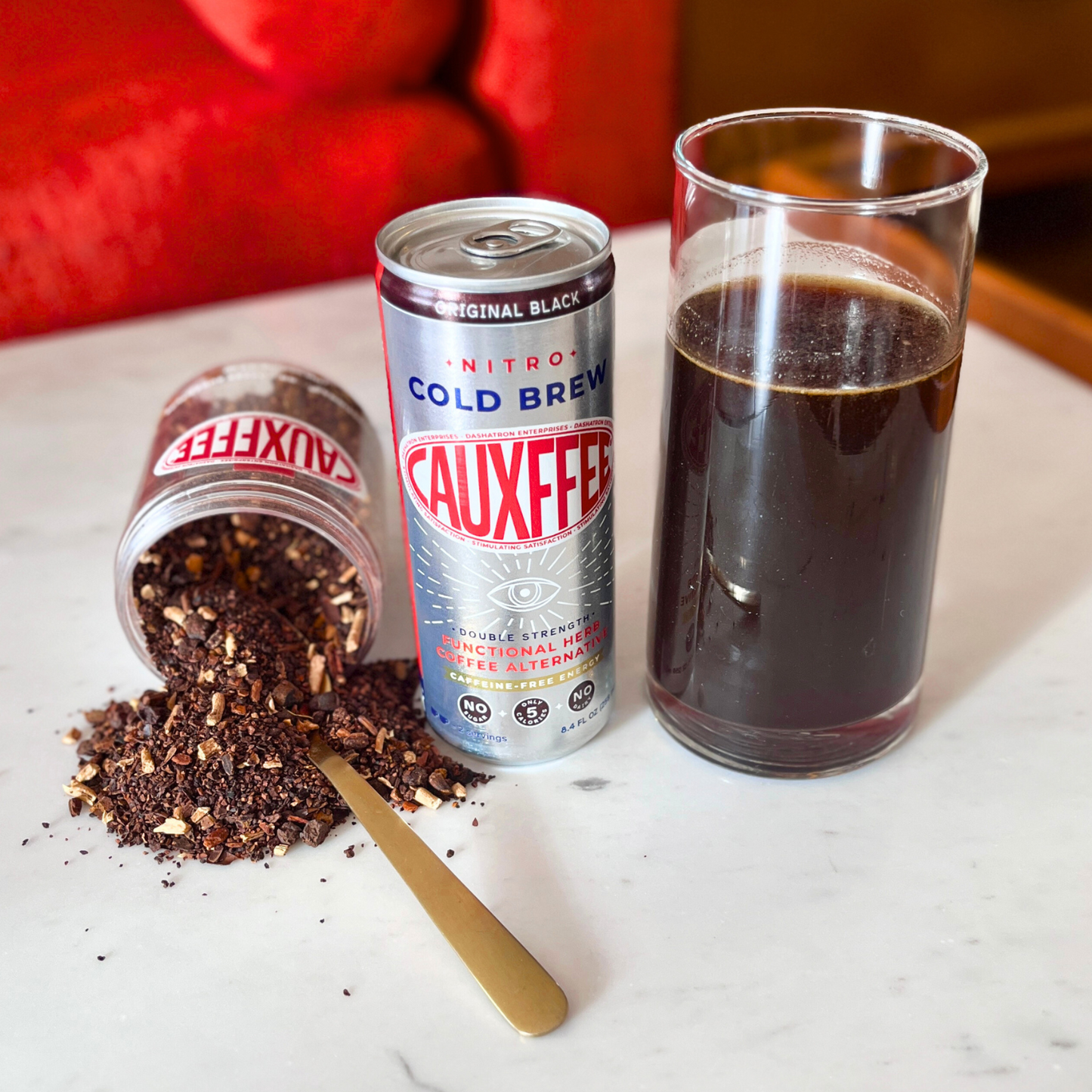 Cauxffee can, Cauxffee ingredients, and a glass of cold brew on a marble surface.