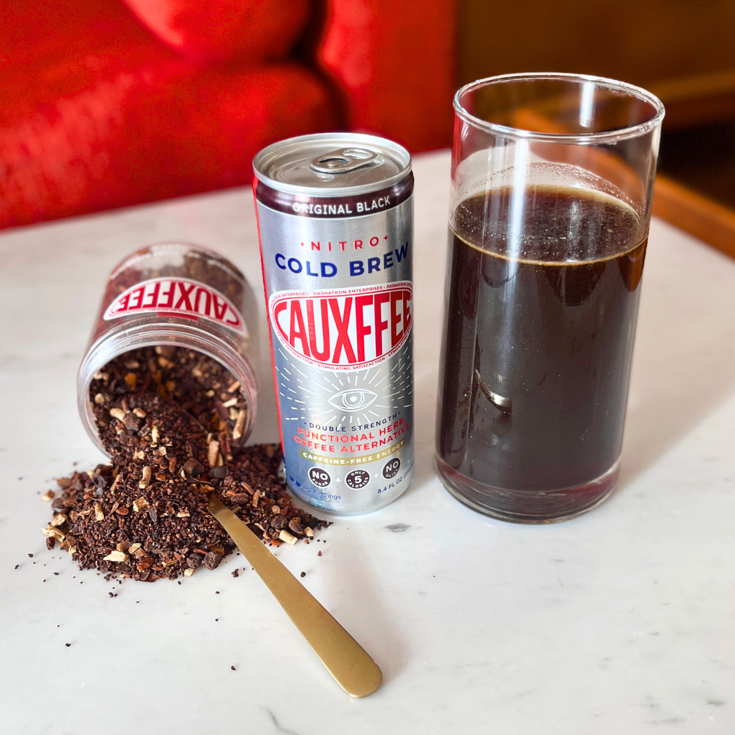 Cauxffee can, Cauxffee ingredients, and a glass of cold brew on a marble surface.